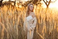 A gorgeous woman in an autumn field illuminated by the warm sun of an evening sunset. Golden ears of corn. Autumn Royalty Free Stock Photo