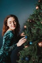 Gorgeous woman in a beautiful dress posing near Christmas tree. Seductive playful female portrait. New Year and Christmas