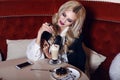 Gorgeous woman with blond hair sitting in cafe with coffee and dessert Royalty Free Stock Photo