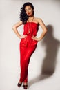 Gorgeous woman with dark hair and tanned body, wears elegant red suit and bijou Royalty Free Stock Photo
