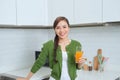 Gorgeous woman drinking a glass of orange juice standing in her kitchen looking at camera Royalty Free Stock Photo