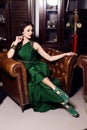 Gorgeous woman in elegant green dress posing in luxurious interior