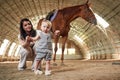 Gorgeous woman with her little baby son is with horse indoors Royalty Free Stock Photo