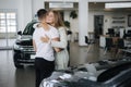 Gorgeous woman hug his husband after buying car in car showroom. Man and woman buy new car. Happy couple have new Royalty Free Stock Photo
