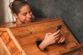 Gorgeous woman playing her mobile phone while using sauna cabinet.Tranquility Royalty Free Stock Photo