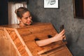 Gorgeous woman playing her mobile phone while using sauna cabinet.Tranquility Royalty Free Stock Photo