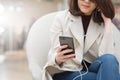 gorgeous woman in trench coat use smartphone listen via ear phone