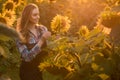 Gorgeous, young, adorable, female farmer examining sunflowers in the middle of a beautiful sunflower field, during a scenic Royalty Free Stock Photo
