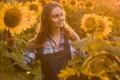 Gorgeous, young, adorable, female farmer standing in the middle of a beautiful green and golden sunflower field during a sunrise Royalty Free Stock Photo