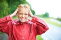 Nothings better than a little fresh rain water. Gorgeous young blonde woman wearing a red raincoat in the rain outdoors Royalty Free Stock Photo