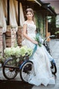 Gorgeous young bride outdoors with bike and basket full of flowers