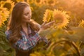 Gorgeous, young, energetic, female farmer examining sunflowers in the middle of a beautiful sunflower field, during a scenic Royalty Free Stock Photo