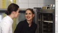 Beautiful female confectioner and her assistant examining merengues in the oven