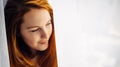 Gorgeous young redhead girl with long hair, close-up, copy space. Portrait of beautiful smiling woman with perfect skin on light Royalty Free Stock Photo