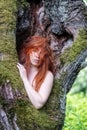 Gorgeous young sexy nature-loving redhead woman elf dryade standing happy close to nature in the trunk of an old willow tree, Love Royalty Free Stock Photo