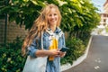 Gorgeous young student female with long blonde hair standing next to the college campus with a reusable bag with books and folders Royalty Free Stock Photo