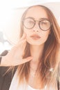 Gorgeous young woman with beautiful lips in fashionable glasses in straw white elegant stylish hat in black trendy jacket posing Royalty Free Stock Photo