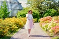 Gorgeous young woman with blond hair in hat posing in a blooming garden.