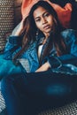 Gorgeous young woman in blue jeans laying on sofa with trow pillows