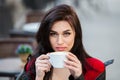 Gorgeous young woman with cup of coffee in city street. Coffee break.  Stylish hipster girl drinking coffee in street. Royalty Free Stock Photo