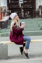 Gorgeous young woman with cup of coffee in city street. Coffee break. Coffee to go. Stylish hipster girl drinking coffee in street Royalty Free Stock Photo