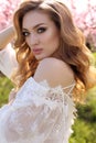 gorgeous young woman in elegant dress posing in garden with blossom peach trees Royalty Free Stock Photo