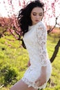 gorgeous young woman in elegant dress posing in garden with blossom peach trees Royalty Free Stock Photo