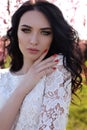 gorgeous young woman in elegant dress posing in garden with blossom peach trees Royalty Free Stock Photo