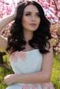 gorgeous young woman in elegant dress posing in garden with blossom peach trees Royalty Free Stock Photo