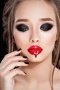 Gorgeous Young Woman face portrait. Beauty Model Girl with bright eyebrows, perfect make-up, red lips, touching her face Royalty Free Stock Photo