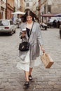 Gorgeous young woman holding cup of coffee and bag, smiling and Royalty Free Stock Photo