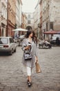 Gorgeous young woman holding cup of coffee and bag, smiling and Royalty Free Stock Photo