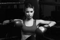 Woman in boxing gloves sitting in corner of ring