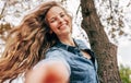 Gorgeous young woman with long hair smiling, wearing blue denim shirt taking the hand to follow. The beautiful female has a joyful