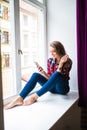 Gorgeous young woman with long red hair checking email and sending sms message on mobile phone Royalty Free Stock Photo