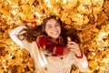Gorgeous young woman lying among yellow autumn leaves, looking at camera and smiling, top view Royalty Free Stock Photo