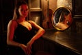 Sad sexy young woman in black dress sitting in dark room of retro bar Royalty Free Stock Photo