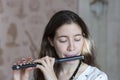 A gorgeous young woman sitting and playing the flute piccolo Royalty Free Stock Photo