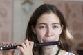 A gorgeous young woman sitting and playing the flute piccolo