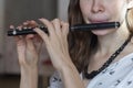 A gorgeous young woman sitting and playing the flute piccolo