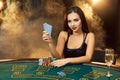 Gorgeous young woman sitting at poker table with glass of champagne