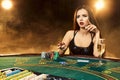 Gorgeous young woman sitting at poker table with glass of champagne