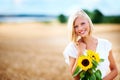 Shes a natural beauty in her element. Gorgeous young woman smiling in a wheat field while holding some sunflowers. Royalty Free Stock Photo