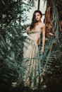 Woman wearing long evening fashionable dress posing in forest. Beauty and fashion concept Royalty Free Stock Photo