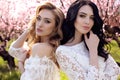 gorgeous young women in elegant dress posing in garden with blossom peach trees Royalty Free Stock Photo