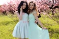 gorgeous young women in elegant dress posing in garden with blossom peach trees