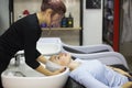 Gorgeous young woman smiling while professional hairdresser wrapping her wet hair in a towel after washing preparing for a haircut