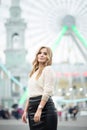 Gorgeus blonde woman in leather skirt posing on the ferris wheel background