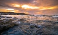 Gorgeus sunset over sea with waves, rocks and traditional greek village of Milatos, Crete Royalty Free Stock Photo