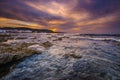 Gorgeus sunset over sea with waves, rocks and traditional greek village of Milatos, Crete Royalty Free Stock Photo